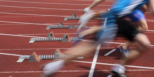 Mehrere Sprinter nebeneinander starten aus Startblöcken.